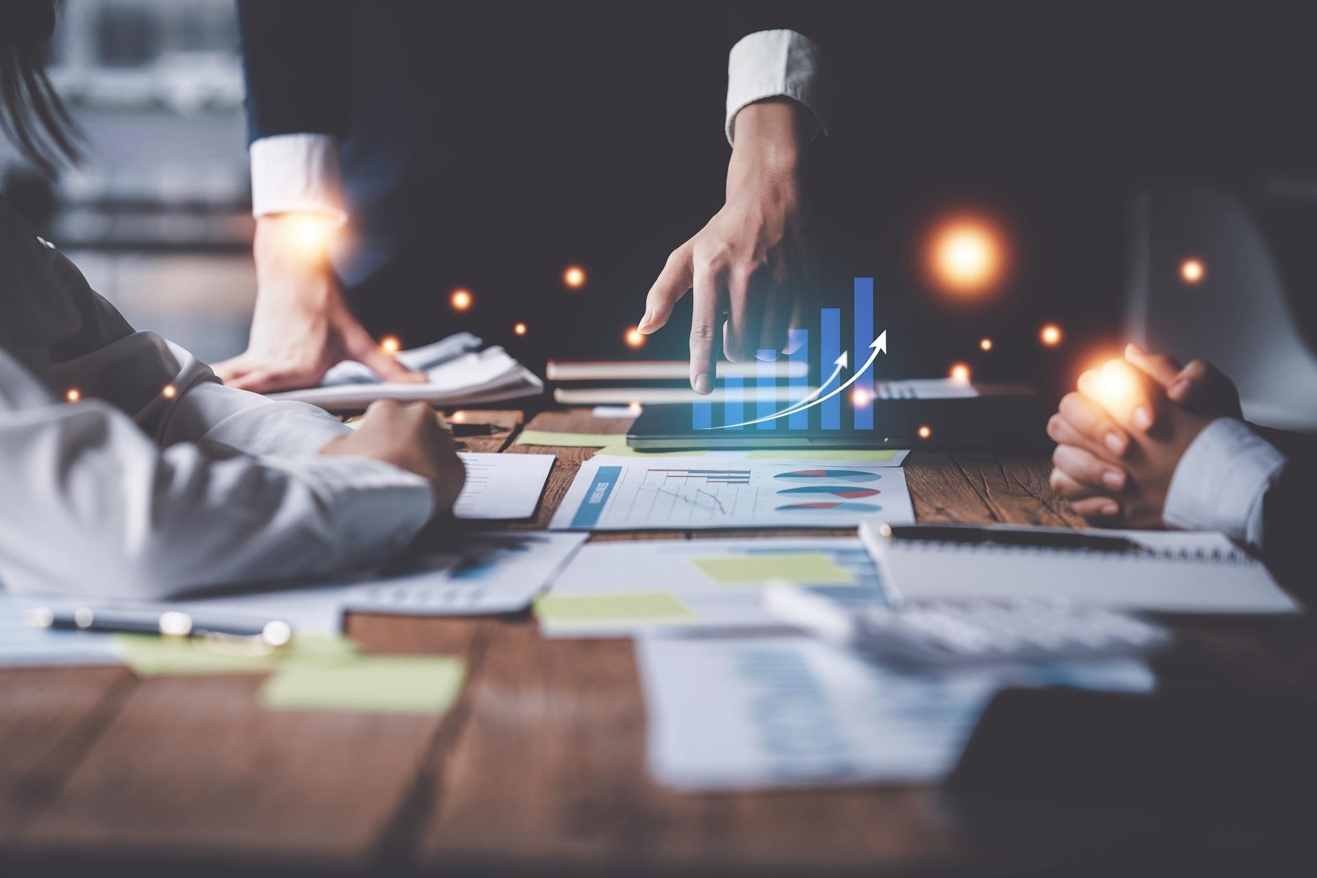 Haende zeigen auf wachsende Diagramme mit digitalen Elementen | AEO